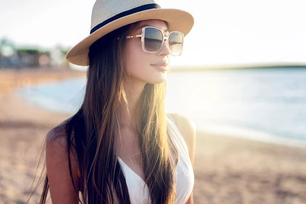 年轻快乐的女孩享受暑假 在海滩散步 一个有着长长的黑发 戴着太阳镜和帽子的漂亮女人的画像 真正的人民生活方式 — 图库照片