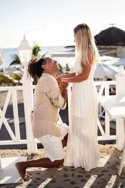 一个快乐的男人在海滩上向他美丽的女人求婚的浪漫场景 真正的人的生活方式爱 多族裔夫妇 — 图库照片