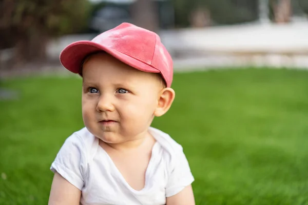 晴れた日の水平方向の画像に緑の芝生の上に座ってかわいい赤ちゃんの男の子 白人の子供が帽子をかぶって — ストック写真