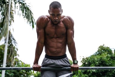 Genç yakışıklı sporcu parktaki barlarda jimnastik yapıyor. Açık spor salonu. Sağlıklı bir yaşam tarzı. Spor. Hobi olarak. Kas gücü