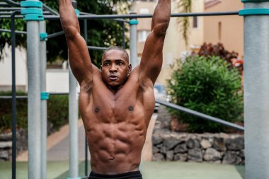 Genç yakışıklı sporcu parktaki barlarda jimnastik yapıyor. Açık spor salonu. Sağlıklı bir yaşam tarzı. Spor. Hobi olarak. Kas gücü