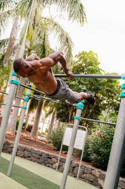 Genç yakışıklı sporcu parktaki barlarda jimnastik yapıyor. Açık spor salonu. Sağlıklı bir yaşam tarzı. Spor. Hobi olarak. Kas gücü