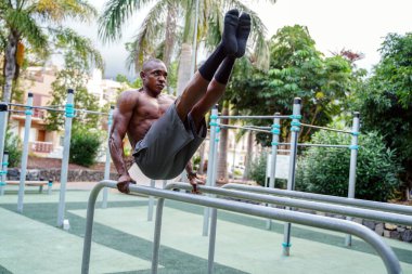 Genç yakışıklı sporcu parktaki barlarda jimnastik yapıyor. Açık spor salonu. Sağlıklı bir yaşam tarzı. Spor. Hobi olarak. Kas gücü