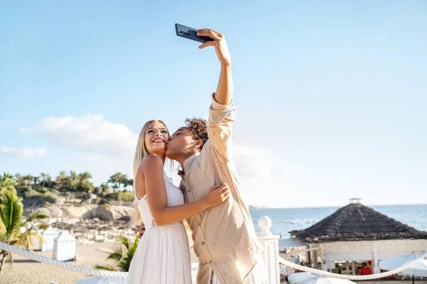 Aşık Mutlu Çift Öpüşüyor Sahilde Akıllı Telefonuyla Selfie Çekiyor Balayı — Stok fotoğraf