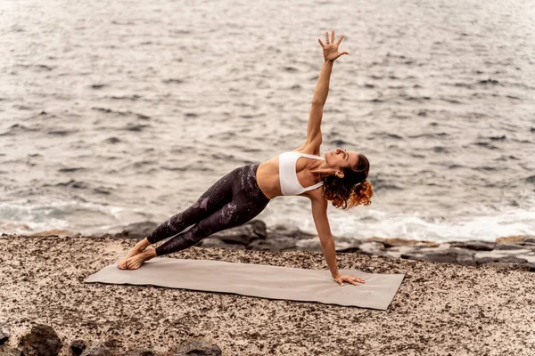 活跃的女运动员站在海岸上做瑜伽姿势 早上例行公事呼吸运动 心事重重 — 图库照片