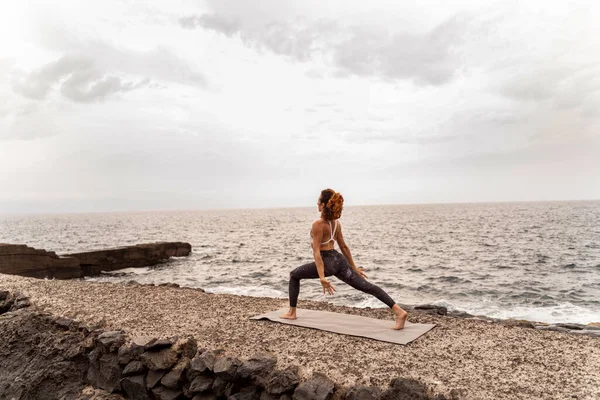 活跃的女运动员站在海岸上做瑜伽姿势 早上例行公事呼吸运动 心事重重 — 图库照片