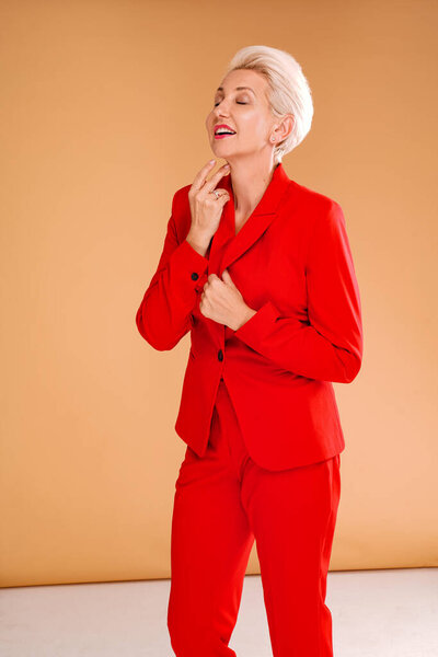 Fashion photo of elegant business woman in a red suit. Beautiful confident and attractive blonde caucasian lady with short hairstyle. Studio shot.