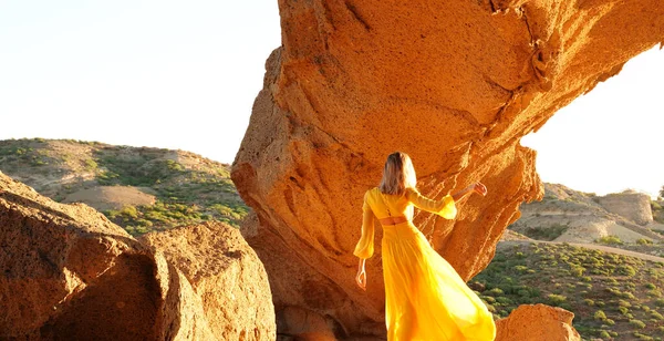 テネリフェ島の岩の洞窟から日の出を見てマキシイエローのドレスを着た女性は バックビュー — ストック写真