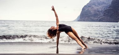 Sahilde yoga pozu veren aktif sporcu kadın. Sabah rutini. Nefes egzersizi. Farkındalık