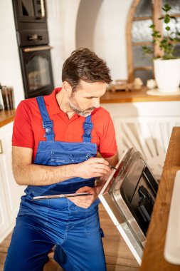 Tesisatçı mutfakta bulaşık makinesini tamir ediyor. Çalışırken çalışan biri..