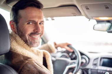 Yakışıklı, gülümseyen bir adam yeni araba kullanıyor, yolculuğun tadını çıkarıyor, kameraya bakıyor. Bir sürü kopyalama alanı