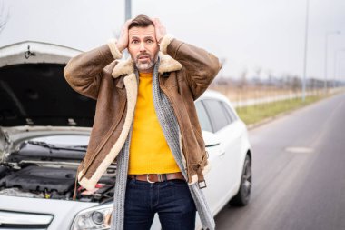 Yolun kenarında bir adam bozuk bir arabanın önünde duruyor, sigorta şirketini bekliyor. Gerçek insanların duyguları, yüz ifadeleri. Motor sorunu.
