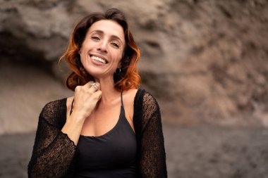 Doğal gülümseyen kadın portresi, kameraya bakıyor. Gümüş takılar takan güzel bir kız. Kayalık arka plan. Bir sürü kopyalama alanı.