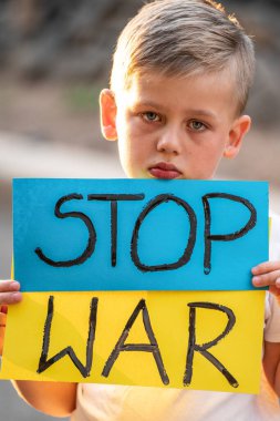 Savaşa karşı çocuk. Mavi sarı bayraklı Ukraynalı çocuk mavi duvarda savaş işaretini protesto ediyor. Sivillerin tahliyesi. Ukrayna 'ya özgürlük. Rus saldırısını durdurun. Destekle.