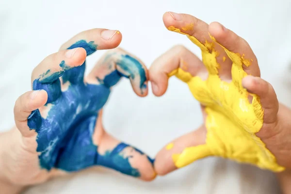 Children's hands painted in blue and yellow color in heart shape, flag of Ukraine. Stop war symbol. Ukrainian Independence Flag Day. Constitution day.