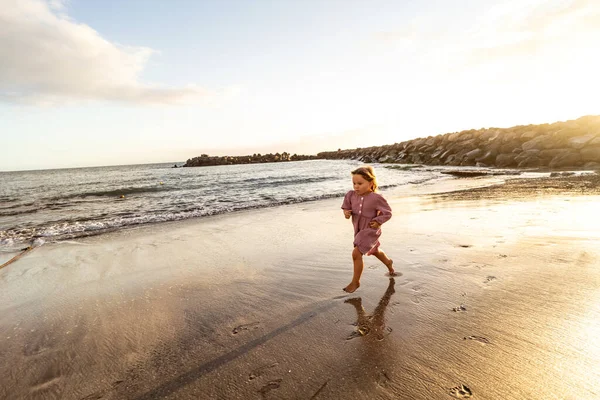 日落时 可爱的小女孩在美丽的沙滩上跑着 快乐极了 大量的复制空间 — 图库照片