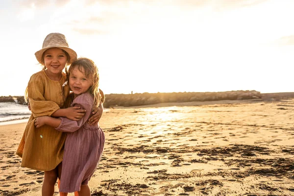 孩子们在海滩上玩耍 日落时小姐妹们在海滨玩得很开心 家庭暑假让人兴奋 大量的复制空间 — 图库照片