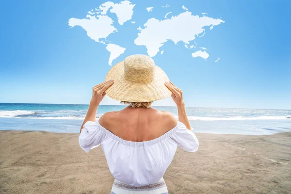一个戴着草帽的女人在海滩享受阳光的概念性照片 后视镜蓝色天空中的世界地图形状的云 大量的复制空间 — 图库照片