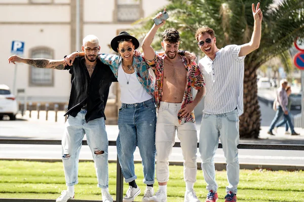 Bir grup modaya uygun genç arkadaş şehirde birlikte eğleniyor, oynuyor, gülüyor ve sosyal medya için içerik oluşturuyor. Dört kişi. Arkadaşlık. Mutluluk. Gerçek insan yaşam tarzı..