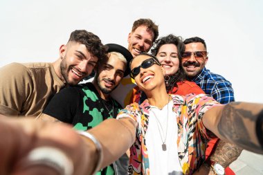 Bir grup mutlu genç arkadaş cep telefonuyla selfie çekerken eğleniyor ve gülüyorlar. Çeşitli bin yıllık insanlar birlikte zaman geçiriyorlar. Arkadaşlık kavramı. Gerçek insan yaşam tarzı.
