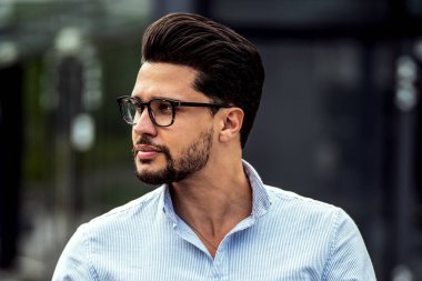 Ofis dışında cep telefonu uygulaması kullanan yakışıklı bir iş adamı. Başarılı bir adam iş için akıllı telefon tutuyor. Açık hava fotoğrafı. Zarif moda tarzı.