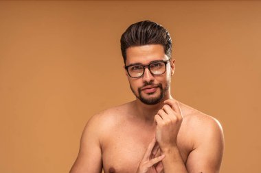 Moda gözlük takan, stüdyo arka planında izole bir şekilde kameraya bakan yakışıklı, üstsüz genç bir adamın güzel portresi. Erkek derisi. Bir sürü kopyalama alanı