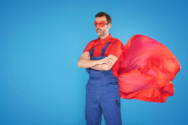 穿着红色斗篷和面具的英俊的杂工作为超级英雄被隔离在蓝色的工作室背景下 修理家的概念 大量的复制空间 — 图库照片