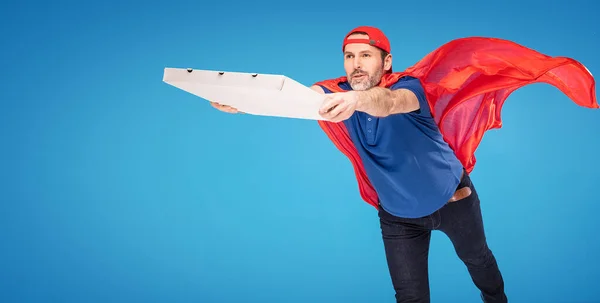 超级英雄披萨送货的家伙在蓝色工作室背景 身穿红色斗篷 大量的复制空间 — 图库照片