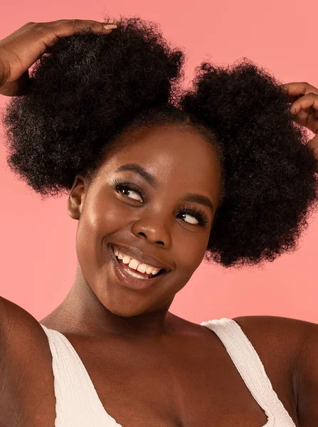 Doğal makyajlı ve modaya uygun saç stili olan, pastel pembe stüdyo arka planında poz veren Afrikalı bir kadın. Gerçek insanların duyguları, dişlek gülümsemeleri. Güzellik portresi.