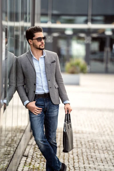 Handsome businessman posing outside business centre. Portrait of a confident young bearded male model in the city