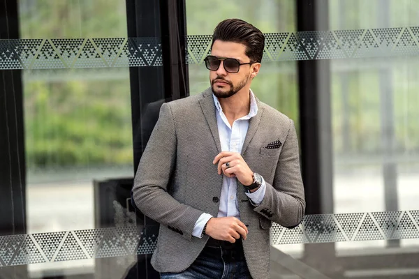 Handsome businessman posing outside business centre. Portrait of a confident young bearded male model in the city