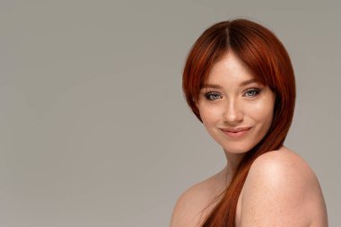 Natural young redhead woman with beauty face and freckles. Healthy facial skin care. Beautiful girl with delicate makeup, red hair looking at the camera with smile. Copy space