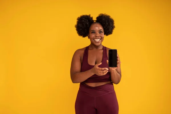 Спортивна Африканська Жінка Показує Мобільний Телефон Новим Додатком Позуючи Жовтому — стокове фото