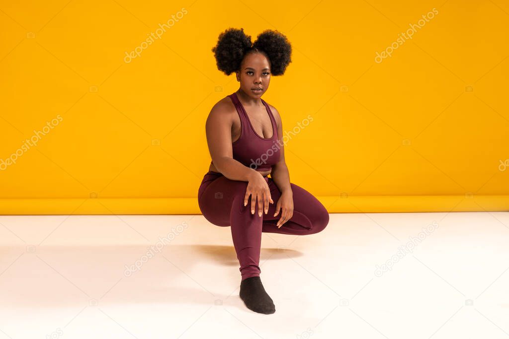 Happy plus size woman posing in sporty black fashionable clothes, smiling to the camera. Copy space. Sports and weight loss concept. Studio shot. Full length photo