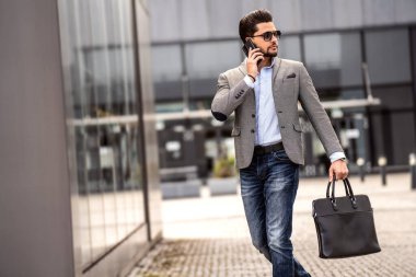 Yakışıklı, iyi giyimli, şık güneş gözlüğü takan ve dışarıda poz veren genç bir adam. İş adamı. Erkek modeli.