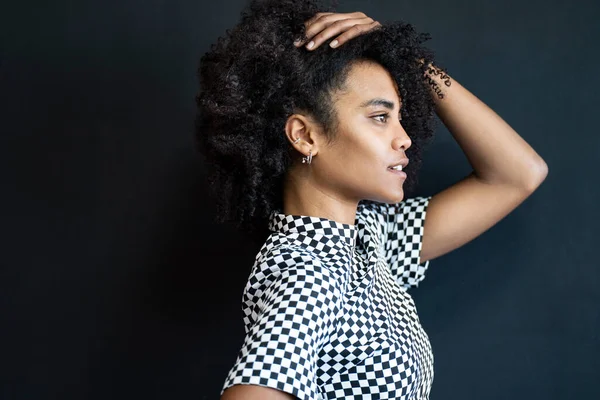 Portrait of young woman with afro hairstyle on the black background. Profile. Natural beautiful girl with curly hair. Fashionable female model
