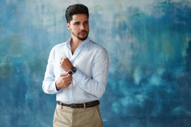 Elegant handsome businessman in fashionable clothes wearing hand watch, looking to the side. Portrait of bearded man. A lot of copy space.  clipart