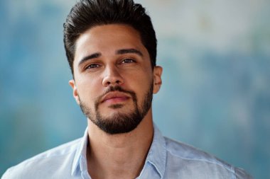 Close up portrait of manly, attractive, handsome, bearded man looking at camera. Guy with brown beautiful eyes