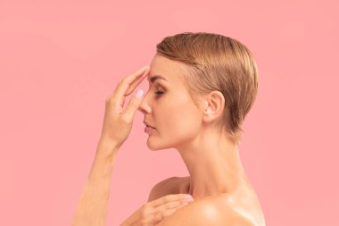 Sarışın, kısa saçlı ve gözleri kapalı beyaz bir kadının güzel stüdyo portresi. Doğal, hassas makyaj. Güzel saç kesimi. Profil görünümü. Pembe pastel arkaplan