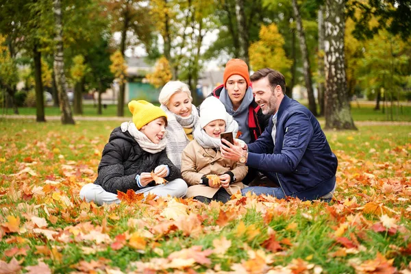 五个人的家庭在金秋公园共度时光 一起玩乐 在手机上自拍 或在网上与人聊天 真正的人民生活方式概念 — 图库照片