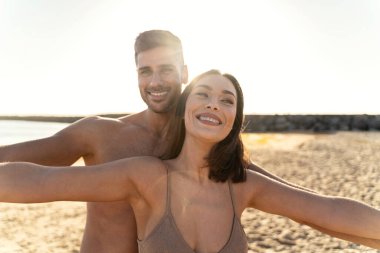 Romantik genç çift yaz tatilinin tadını çıkarıyor. Mutlu koca ve güzel eş, balayı boyunca sahilde birlikte vakit geçiriyorlar. Mutlu gülümseyen insanlar. Gerçek yaşam tarzı.