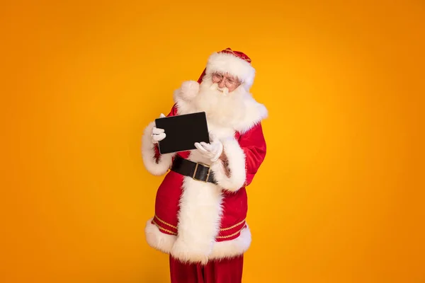 Веселий Санта Клаус Показує Цифровий Планшет Камери Розмістивши Жовтому Фоні — стокове фото