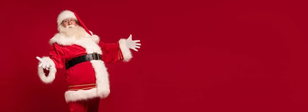 形象的好老圣诞老人摆姿势与开放的手和微笑在一个红色工作室的背景 圣诞快乐 新年快乐 复制空间 圣诞节销售 折扣概念 — 图库照片