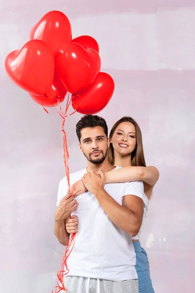 圣瓦伦丁节恋爱中的年轻夫妇 英俊快乐的男人和微笑的女人摆出心形的红色气球 真是惊喜啊真正的爱情 关系和人类情感概念 — 图库照片