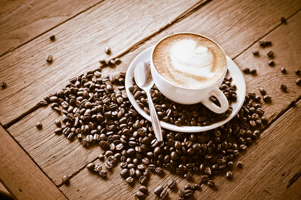 Tasse à café et grains de café sur table en bois — Photo