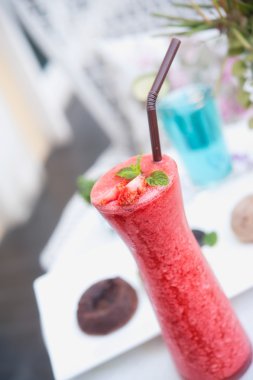 Masanın üzerinde cam içinde çilekli smoothie.