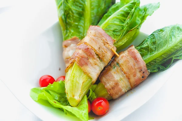 Gröna cos inlindad i bacon på vita skålen — Stockfoto