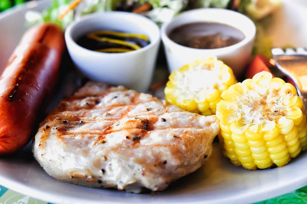 Steak de porc à la saucisse et salade de légumes sur plat blanc — Photo