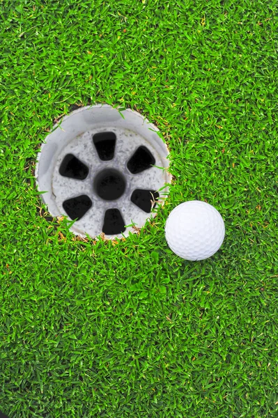 Golfbal en golf gat op het groene gras — Stockfoto