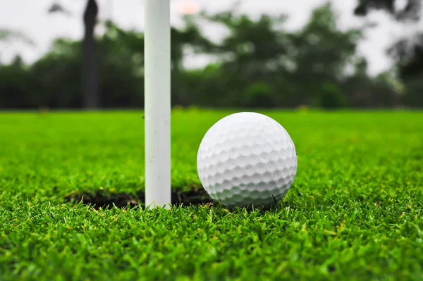 Golf ball on lip of cup — Stock Photo, Image